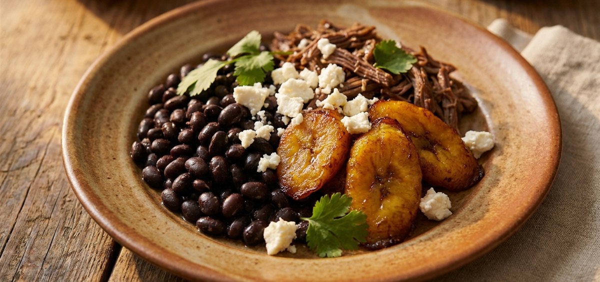 Close overhead shot of a plate combining sweet plantains, salty white cheese, black beans and shredded beef in harmony